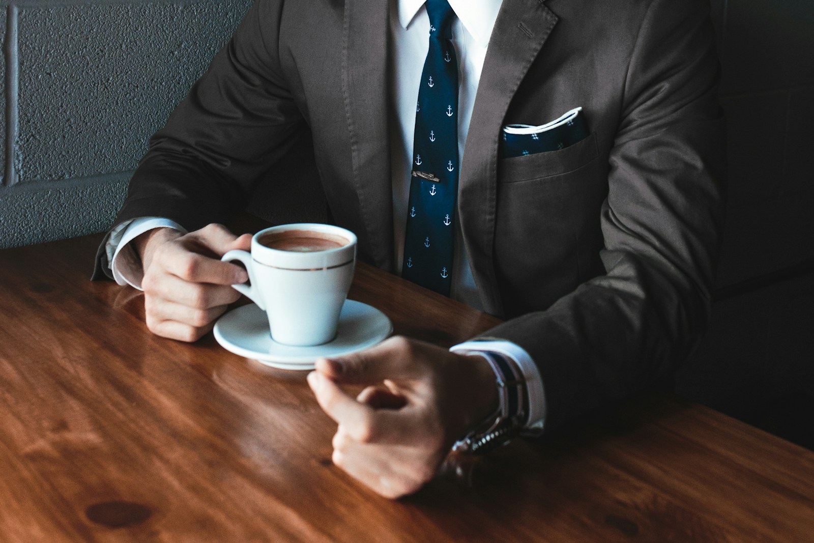 Photo by Andrew Neel man holding cup filled with coffee on table